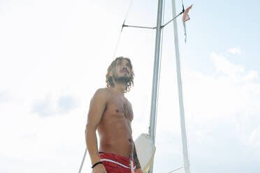 Mann auf einem Segelboot in flachem Wasser - CUF56234