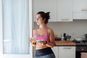 Woman leaning against kitchen door - CUF56243