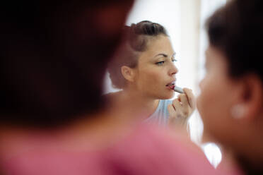 Friends putting on makeup at mirror - CUF56245