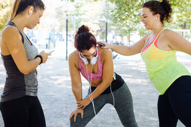 Friends exercising and using cellphone in park - CUF56263