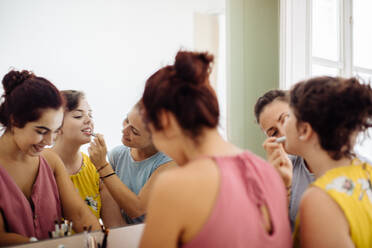 Freunde schminken sich vor dem Spiegel - CUF56266
