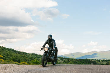 Young male motorcyclist on vintage motorcycle on rural road, Florence, Tuscany, Italy - CUF56270