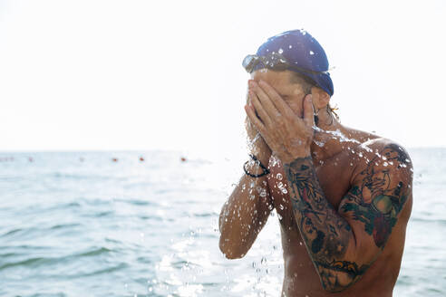Schwimmer spritzt sich Meerwasser ins Gesicht - CUF56280