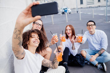 Mixed race group of friends hanging out together in town, taking selfie with mobile phone. - CUF56306