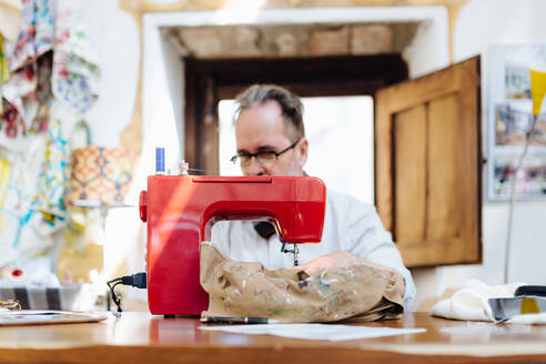 Mann an der Nähmaschine im Kreativstudio - CUF56345