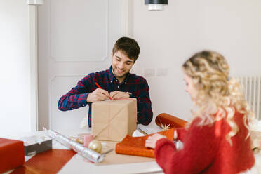 Ehepaar packt Weihnachtsgeschenke zu Hause ein - CUF56354