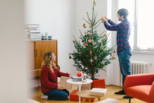 Ehepaar schmückt Weihnachtsbaum zu Hause - CUF56355