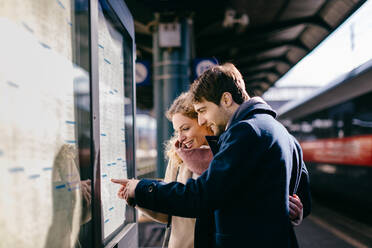 Ehepaar prüft Fahrplan am Bahnhof, Firenze, Toskana, Italien - CUF56386