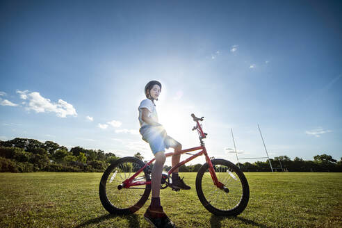 Portrait of boy sitting on his BMX bicycle, wearing cycling helmet. - CUF56458
