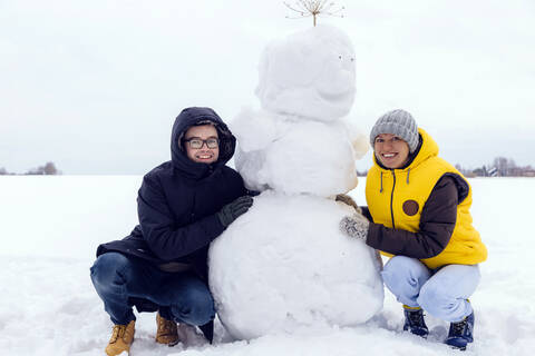 Lächelndes Paar mit Schneemann, lizenzfreies Stockfoto