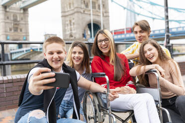 Glückliche junge männliche und weibliche Freunde machen ein Selfie mit der Tower Bridge im Hintergrund, London, UK - WPEF03273