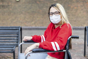 Behinderte Frau im Rollstuhl trägt Gesichtsmaske während des Ausbruchs des Coronavirus - WPEF03288