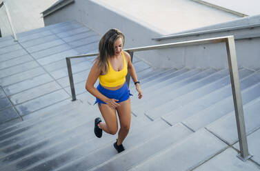 Junge Frau joggt auf einer Treppe - MPPF01025