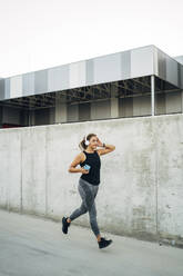 Female jogger in front of grey wall - MPPF01052