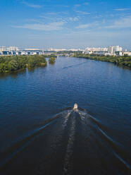 Russland, Oblast Moskau, Moskau, Luftaufnahme eines Motorboots auf der Moskwa mit der Stadt im Hintergrund - KNTF05242