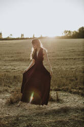Woman standing in fields wearing black dress - GMLF00441