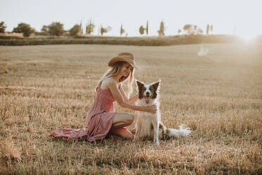 Frau genießt mit Border Collie Hund in Weizenfeld bei Sonnenuntergang - GMLF00456