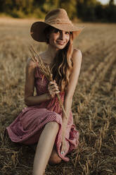 Frau verbringt ihre Freizeit in einem Weizenfeld bei Sonnenuntergang - GMLF00460