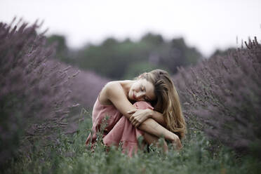 Woman sitting in lavender field - GMLF00471