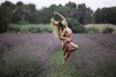 Woman dancing in lavender field - GMLF00472