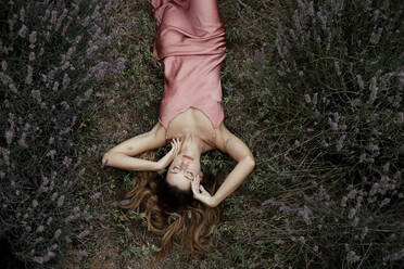 Woman lying in lavender field - GMLF00474