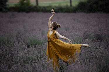 Woman dancing in lavender field - GMLF00480