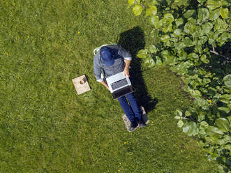 Mann benutzt Laptop im Garten - KNTF05262