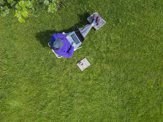 Frau benutzt Laptop im Garten - KNTF05263