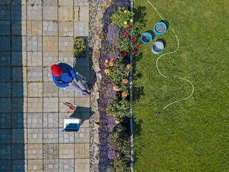 Luftaufnahme einer Frau, die auf einer Terrasse im Garten sitzt - KNTF05264