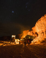 Off-road cars in illuminated desert camp at night - MALF00124