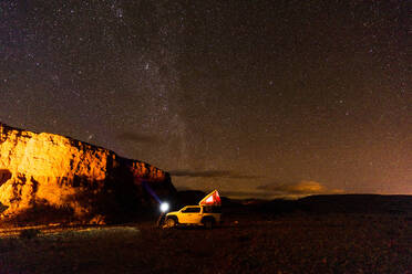 Off-road car in illuminated desert camp at night - MALF00125