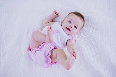 Baby girl touching toes while lying on blanket - EBBF00592
