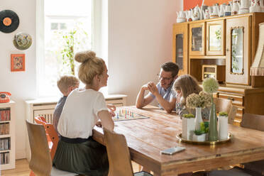 Glückliche Familie spielt Brettspiel am Esstisch zu Hause - MOEF03090