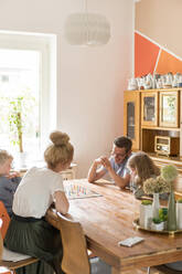 Familie spielt am Wochenende ein Brettspiel am Esstisch zu Hause - MOEF03092