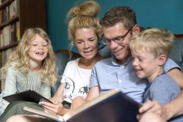 Happy family watching photo album while sitting at home - MOEF03095