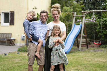 Happy family standing at back yard against house - MOEF03157