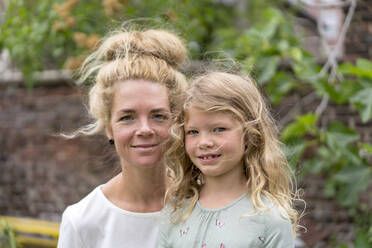Lächelnde blonde Frau mit Tochter im Hinterhof - MOEF03168