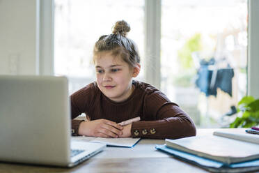 Mädchen mit Buch und Laptop beim Lernen zu Hause - JOSEF01479
