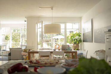 Living room with dining table against door and window during sunny day - JOSEF01489