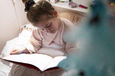 Mädchen, das im Schlafzimmer sitzend ein Buch liest - JOSEF01505