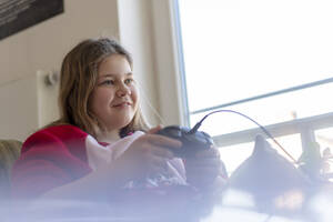 Lächelndes Mädchen spielt ein Videospiel zu Hause - JOSEF01516
