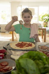 Cute smiling girl preparing pizza over kitchen island - JOSEF01518