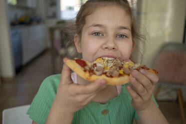 Nettes Mädchen isst ein Stück Pizza zu Hause - JOSEF01534