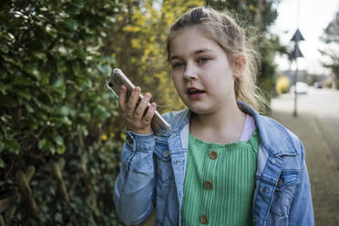 Mädchen mit Smartphone steht bei Bäumen im Park - JOSEF01536