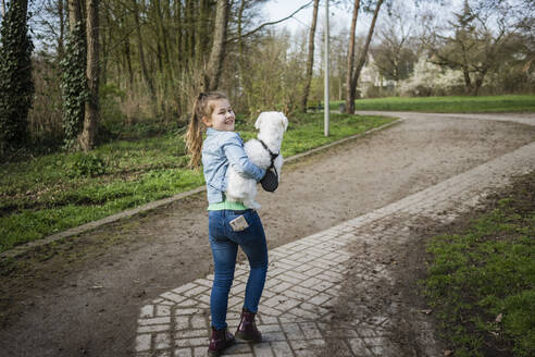 Lächelndes süßes Mädchen mit Hund auf dem Gehweg - JOSEF01537