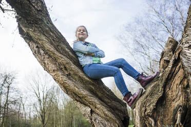 Lächelndes Mädchen mit verschränkten Armen an einen Baumstamm gelehnt im Park - JOSEF01543