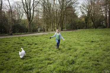 Lächelndes Mädchen läuft mit Hund auf Gras im Hof - JOSEF01545