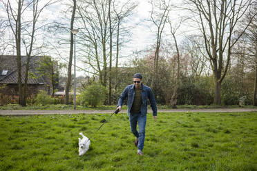 Smiling man running with dog on grass in yard - JOSEF01546