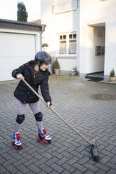 Girl skating while cleaning porch with broom - JOSEF01550