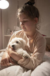 Nettes Mädchen hält Hund im Schlafzimmer sitzend - JOSEF01551